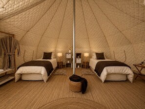 A tent-style room with two beds, a central pole, and a basket on the floor.