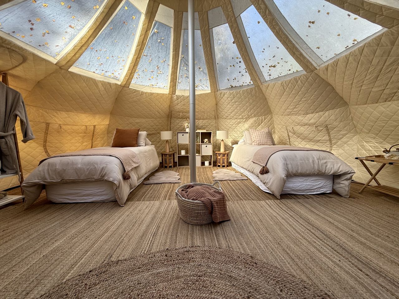 Een knus, tentachtig interieur met twee bedden, een centrale paal en een dakvenster.