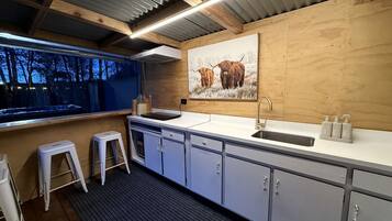 A modern kitchen with a sink, stools, and a painting of yaks.