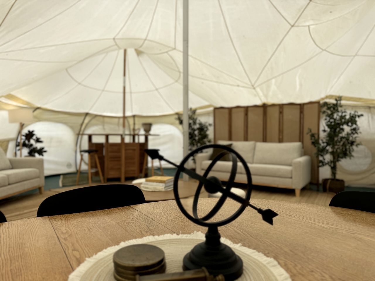 A tented area with a round table, chairs, a globe, and a lamp.