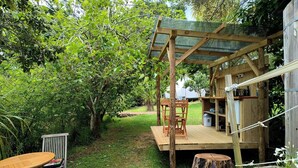 Una terraza de madera con una mesa y sillas, rodeada de follaje y árboles.