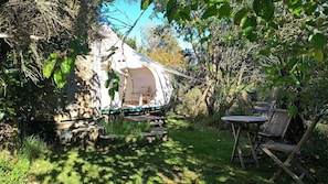 Ein Zelt mit Tisch und Stühlen in einem Garten.