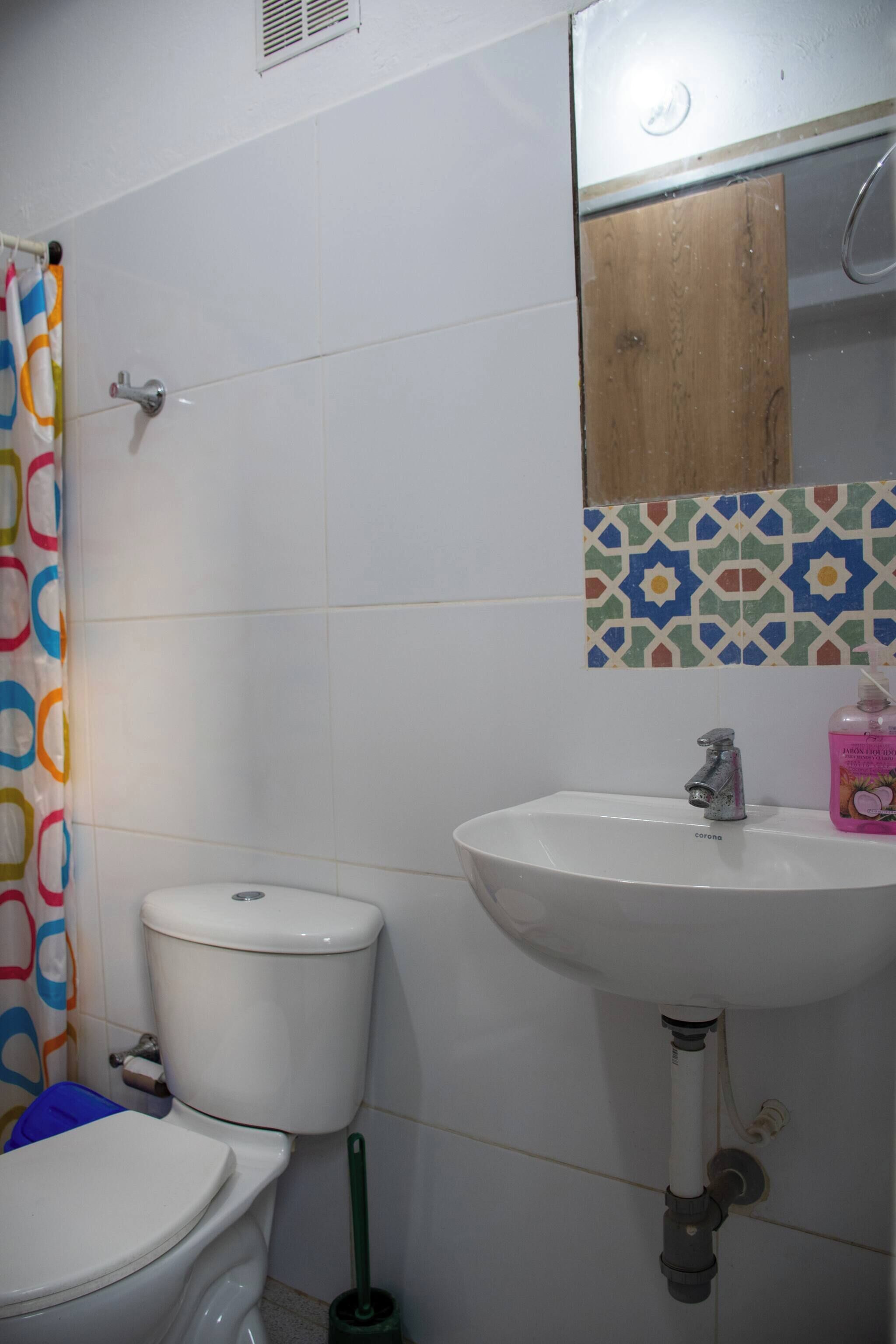 A bathroom with a toilet, sink, and shower curtain.