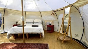 A tent with a bed, a hanging chair, and a small table with a vase. - Secluded Glamping Retreat with Private Wine Barrel Bathroom near Oneroa, Waiheke Island (Waiheke Island)