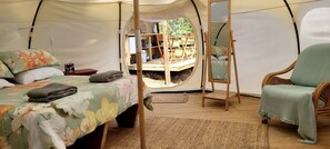 A tent with a bed, a chair, and a small table. - Secluded Glamping Retreat with Private Wine Barrel Bathroom near Oneroa, Waiheke Island (Waiheke Island)
