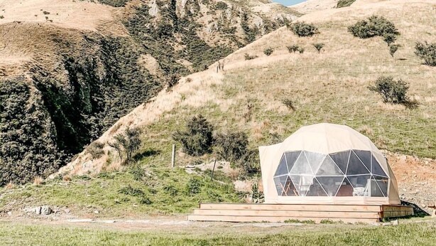 Una estructura de domo geodésico con vistas despejadas del paisaje montañoso circundante.