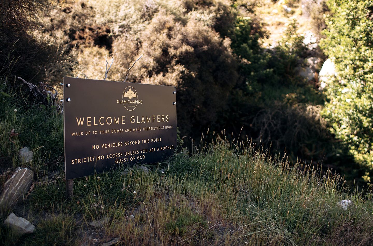 Welkomstbord voor Glam Camping, met een natuurlandschap op de achtergrond.