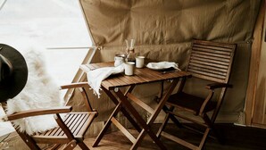 Una habitación con carpa, una mesa de madera, dos sillas, un sombrero y una cámara.
