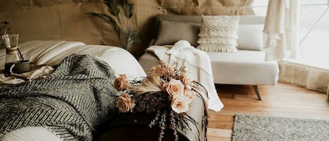 A bedroom with a bed, a suitcase, a bedside table, a lamp, and a window with curtains.