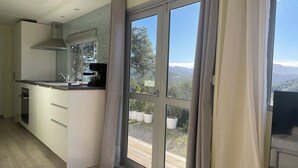 Eine moderne Küche mit Einbauherd, einer Kaffeemaschine und Blick auf einen Balkon mit Topfpflanzen.