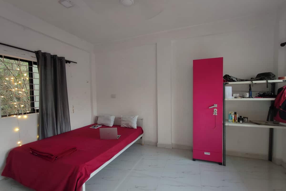 A room with a bed, a desk with shelves, a wardrobe, and a window with curtains.