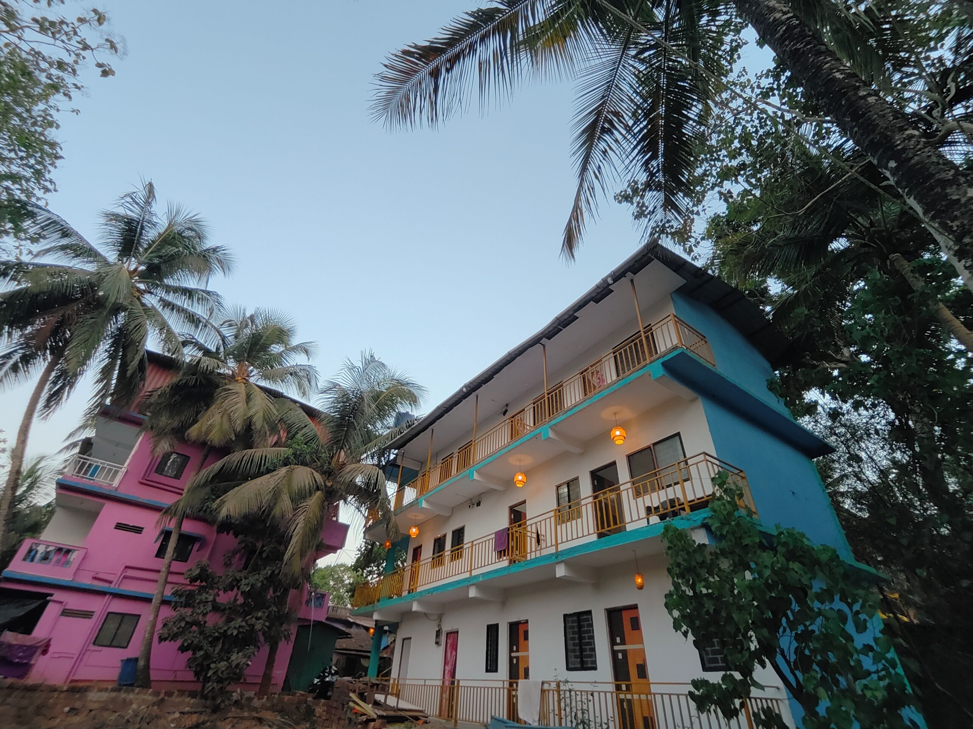 A multi-story building with balconies, surrounded by palm trees.