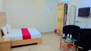 A room with a bed, a small table, a couch, and a TV mounted on the wall. - Hotel Shelton One (Multan)