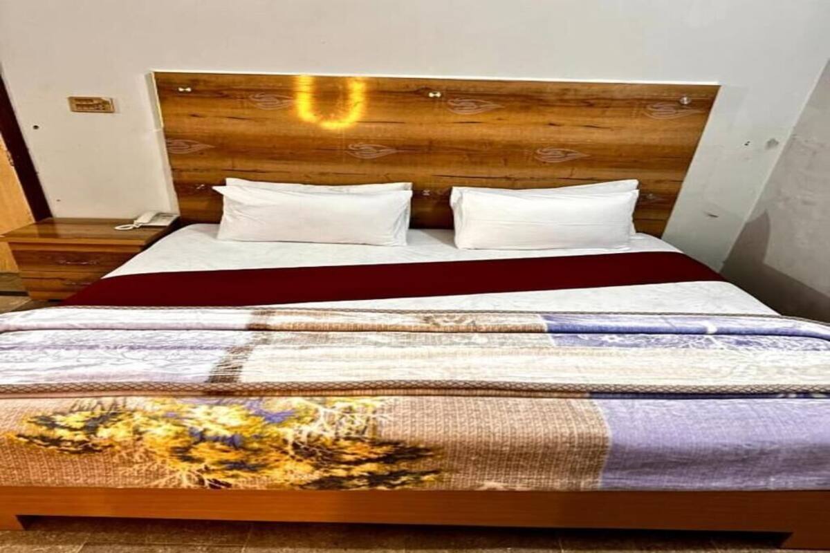 A bed with a wooden headboard, white pillows, and a patterned bedspread.