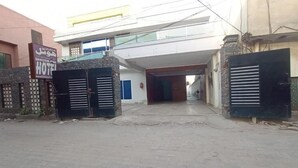 A hotel entrance with a modern design, featuring a large open doorway, a visible fire extinguisher, and a signboard. - Hotel Shelton One (Multan)