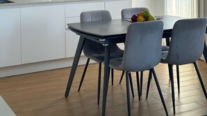 A modern kitchen with white cabinets, a dining table with chairs, a fruit bowl, and a unique spherical light fixture. - Residenza De Gasperi - Location within walking distance of Treviso and Venice (Preganziol)