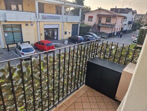 A balcony with a view of parked cars and buildings, including a pharmacy and a residential building. - Residenza De Gasperi - Location within walking distance of Treviso and Venice (Preganziol)