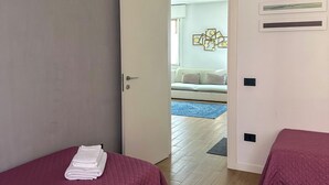 A bedroom with two beds, a door leading to another room, and a wall with three framed pictures. - Residenza De Gasperi - Location within walking distance of Treviso and Venice (Preganziol)