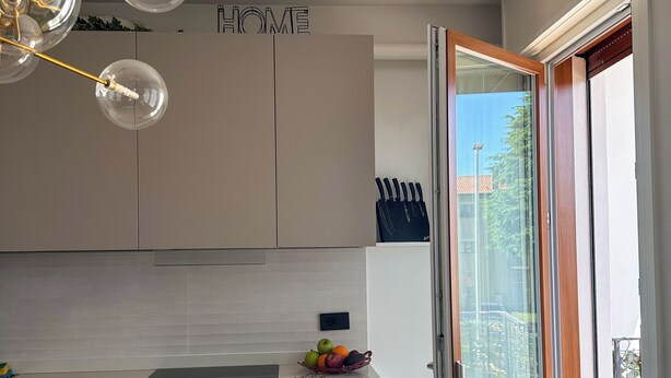 A modern kitchen with a dining area, a chandelier, and a view through a sliding glass door. - Residenza De Gasperi - Location within walking distance of Treviso and Venice (Preganziol)