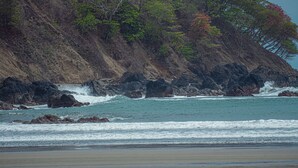 Un paysage côtier caractérisé par des falaises rocheuses, des vagues et une plage.