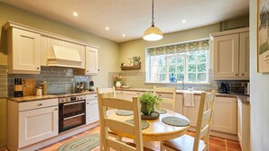 Una cocina con armarios blancos, una mesa de comedor de madera y una lámpara colgante.