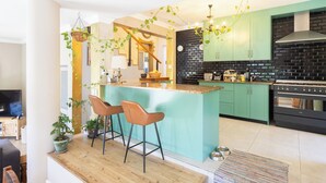 Une cuisine moderne dotée d’un îlot central, de tabourets de bar et d’un coin repas avec un plancher en bois.
