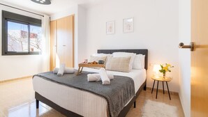 Ein Hotelzimmer mit einem Bett, einem Nachttisch mit Lampe, einem Fenster und einer Tür.