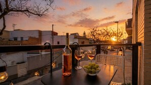 Ein Balkon mit Tisch für zwei Personen, mit Flasche und Gläsern sowie einer Schüssel mit Trauben.