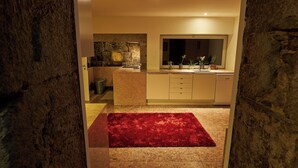 Una cocina moderna con una pared de acento de piedra, una alfombra roja y un espejo grande sobre el lavamanos.