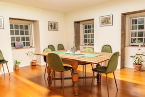 Un coin repas avec une table en bois, des chaises vertes, des plantes en pot et des œuvres d’art accrochées aux murs.