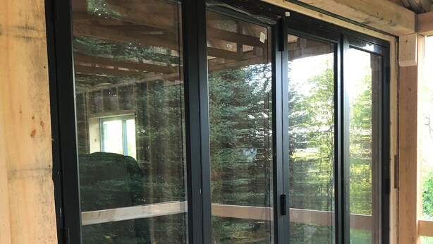 Una terraza de madera con una puerta corredera de vidrio que da a un espacio al aire libre.