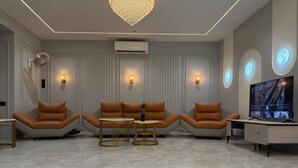 Un salón moderno con sofás de cuero, una mesa de centro, un televisor e iluminación ambiental.