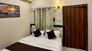 Un dormitorio con una cama, un ventilador de techo, una lámpara de pared, una puerta y un cuadro.