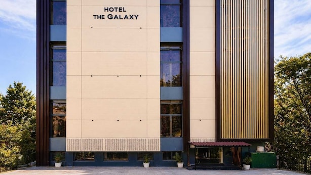 Fachada moderna de un hotel con el nombre 'HOTEL THE GALAXY' visible en grande.