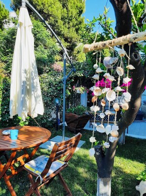 A wooden table with chairs, a white umbrella, and a hanging shell decoration. - Il Canto delle Sirene VIESTE center, with garden, near Pizzomunno beach (Vieste)