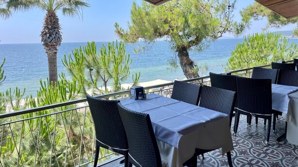A terrace with tables and chairs, overlooking a beach and the sea. - Gülplaj Hotel (Erdek)