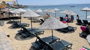 A beach with sun loungers, umbrellas, and a view of the sea. - Gülplaj Hotel (Erdek)