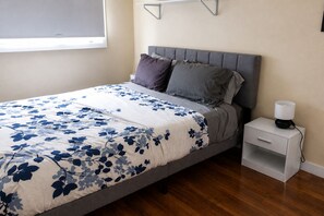 A bedroom with a bed, pillows, a bedside table, and a lamp.