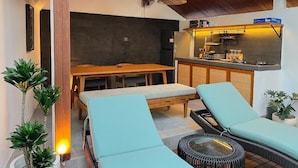 Eine moderne Küche mit eingebautem Herd, einem Essbereich mit Holztisch und -stühlen sowie einer Sitzecke mit Sofa und Sessel.
