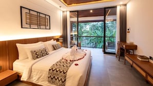 Ein modernes Hotelzimmer mit einem großen Bett, einer Holzbalkendecke, einem Balkon mit Blick auf Grünflächen und einem Essbereich.
