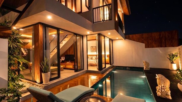 Ein modernes Haus mit Swimmingpool, Sitzgelegenheiten im Freien und einer Treppe zu einer oberen Etage.
