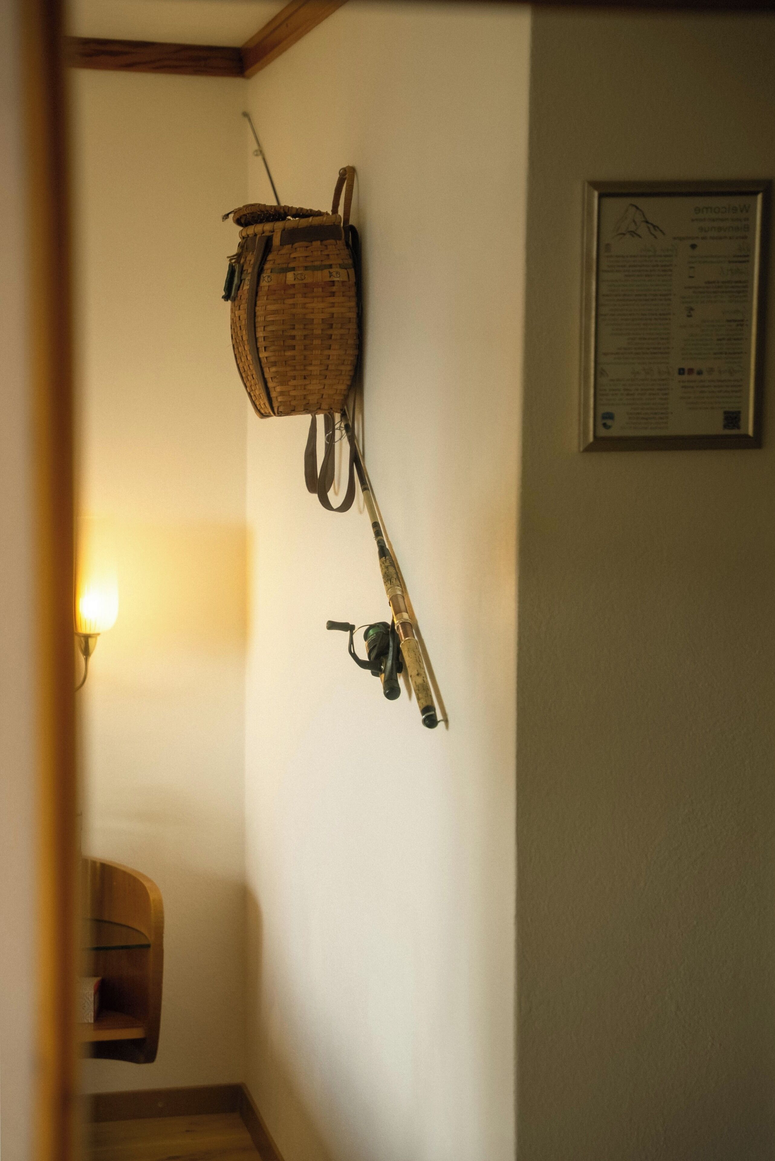 Un angolo di una stanza con un cesto fissato al muro, una locandina informativa incorniciata e una mensola in legno.