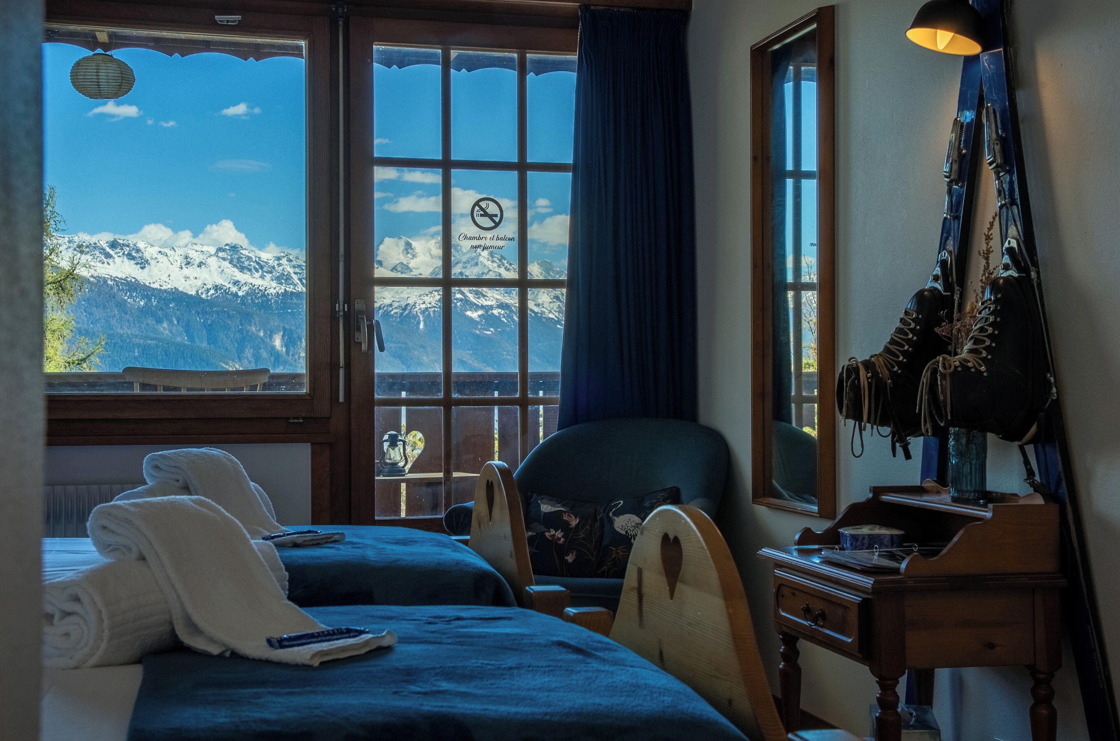 A hotel room with a large window, a chair, a desk, and a bed.