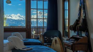 A hotel room with a large window, a chair, a desk, and a bed.