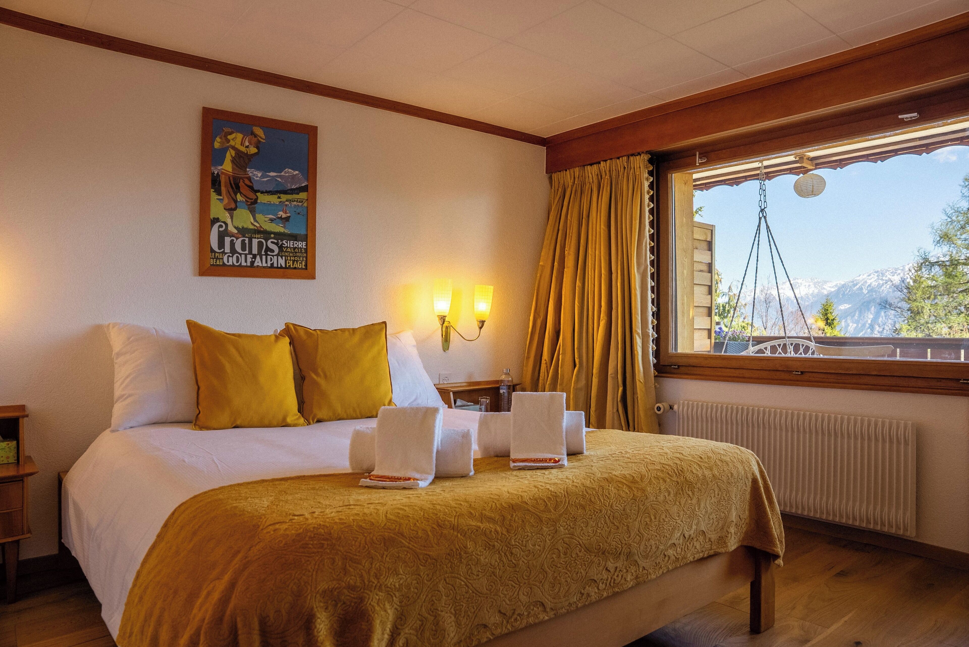 Ein Hotelzimmer mit Bett, zwei Nachttischlampen, einem Fenster mit Vorhängen und einem Poster an der Wand.