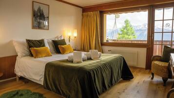 Ein Hotelzimmer mit Bett, Fenster mit Bergblick, Stuhl und Heizkörper.