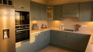 Una cocina con refrigerador de acero inoxidable, dos hornos, un tostador y un lavamanos.