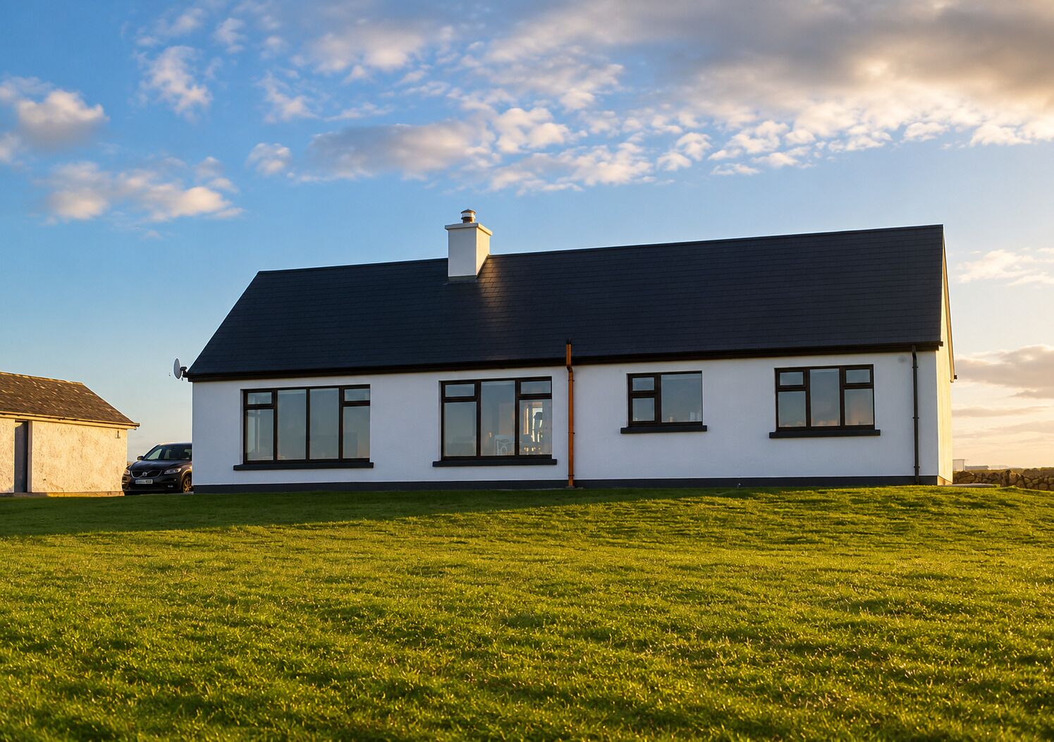 A modern two-story house with a flat roof, large windows, and a well-maintained lawn.