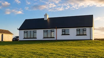 A modern two-story house with a flat roof, large windows, and a well-maintained lawn.