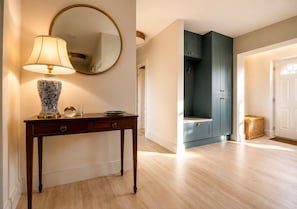 Ein hölzernes Konsolentisch mit einer Lampe und Dekorationselementen, ein Spiegel und ein blauer Schrank in einer Diele.